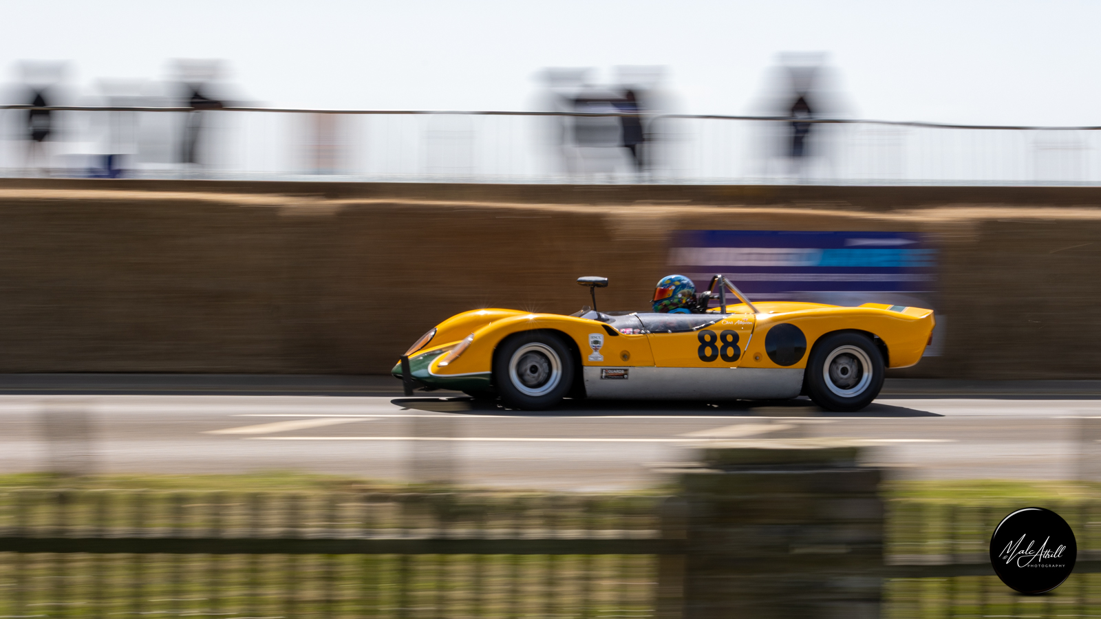 Yellow Lola sports prototype number 88 panning along the seafront