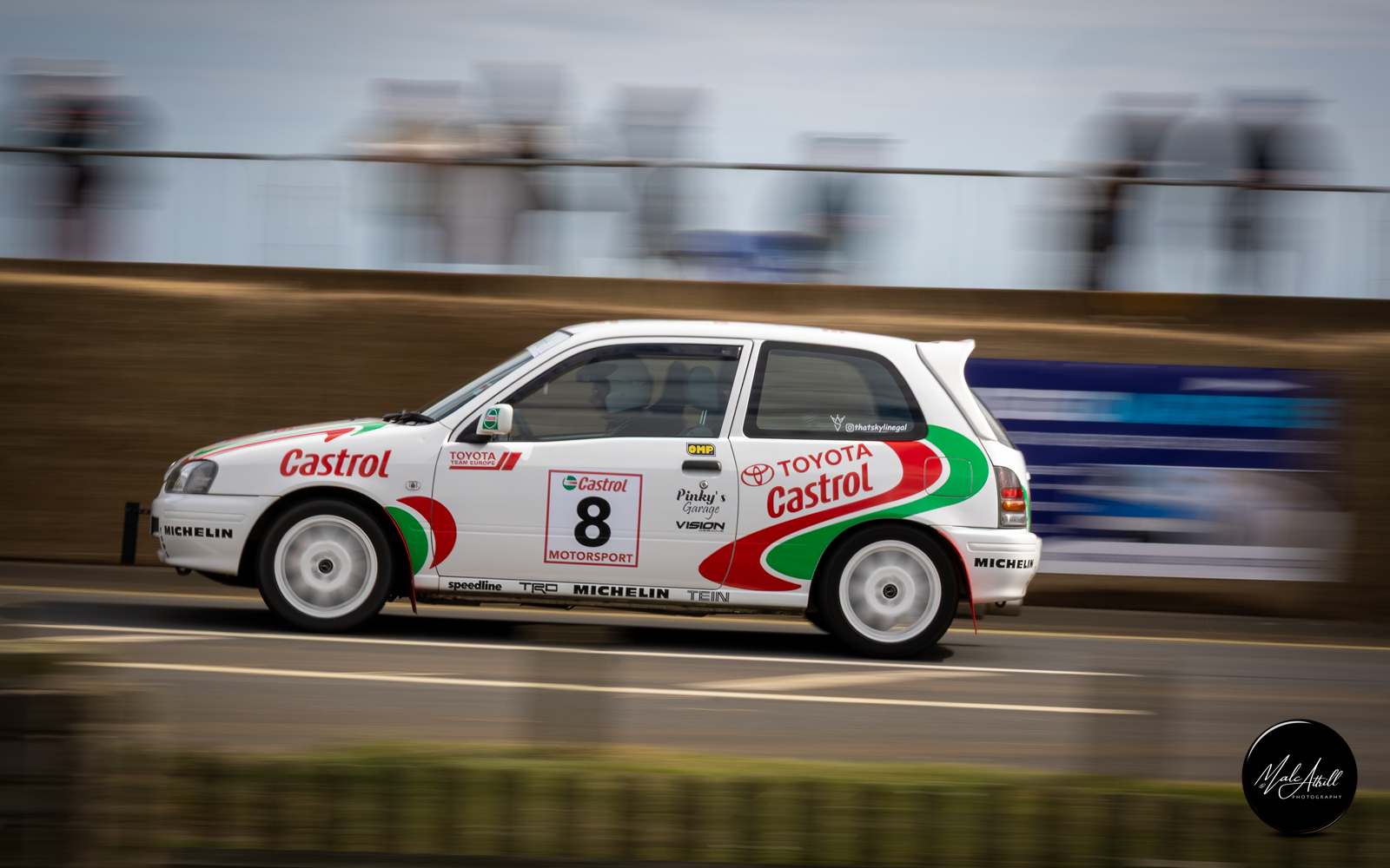 Castrol-liveried Toyota at speed along the seafront in a panning shot